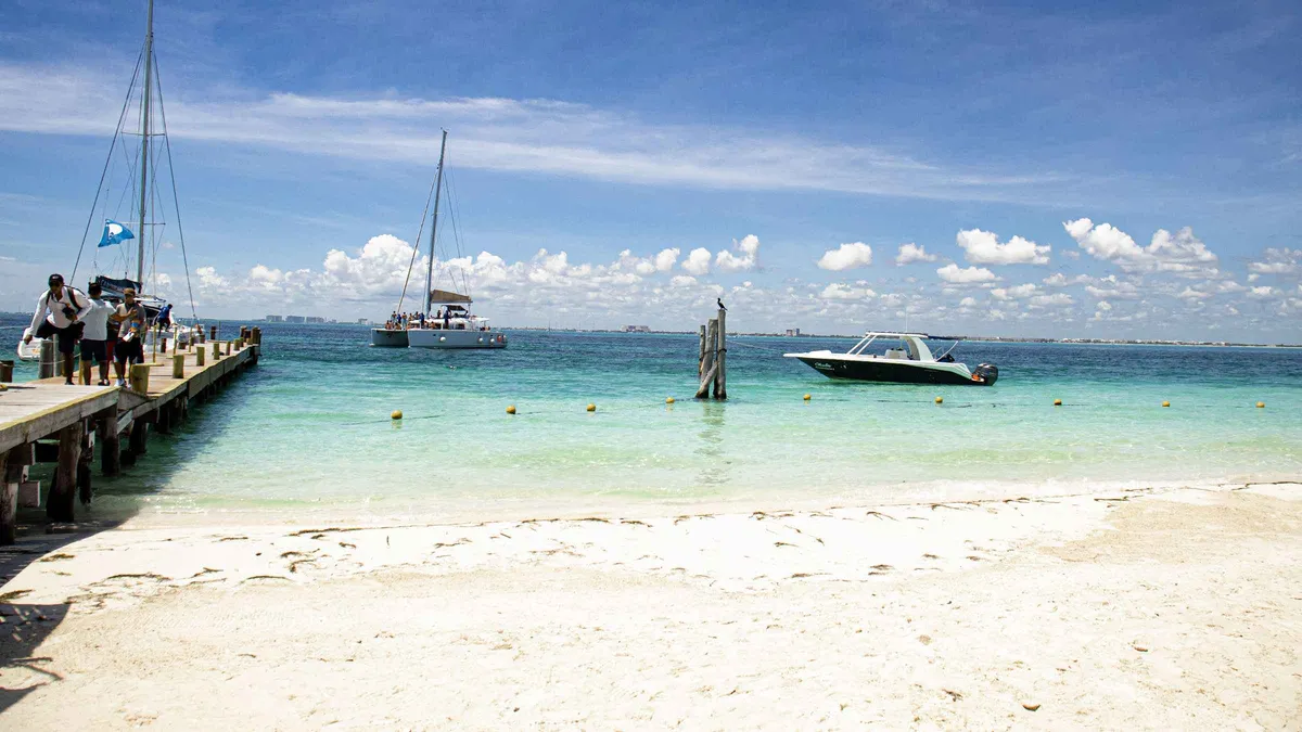 Catamaran with travellers at the turquoise anchored shore off Isla Mujeres on the open bar snorkeling catamaran tour from Cancun, Mexico